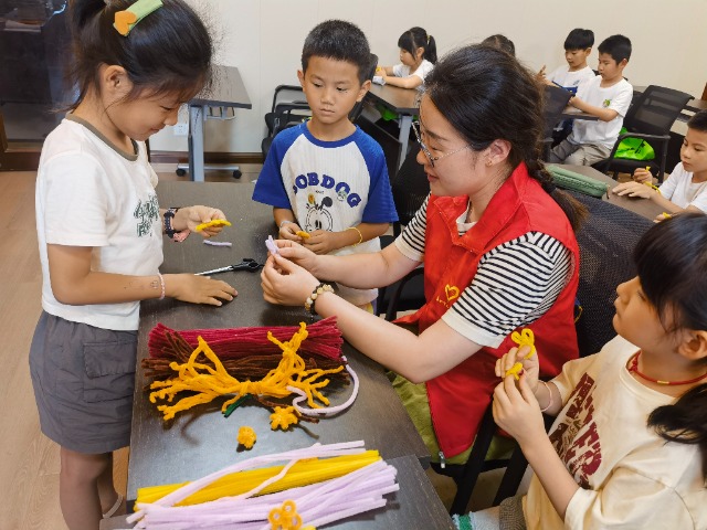 7月12日，在泰州市海陵區(qū)城東街道林湖社區(qū)，泰州市大浦小學(xué)“綠葉”暑期公益班的老師正在教孩子們一起做手工2（拍攝者：泰州市大浦中心小學(xué)  陳惠婷）.jpg